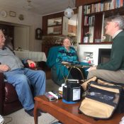 Three people seated in a living room. Two are being interviewed.